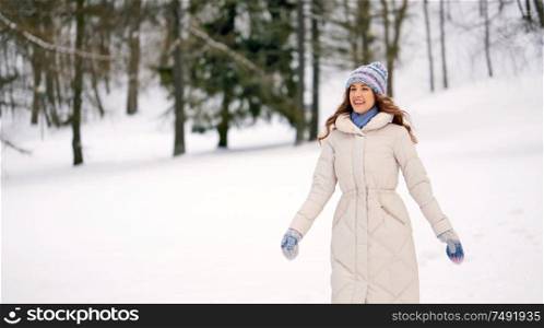 people, season and leisure concept - happy smiling woman outdoors in winter forest. happy smiling woman outdoors in winter forest