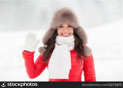 people, season and leisure concept - happy woman in winter fur hat waving hand outdoors. happy woman in winter fur hat waving hand outdoors