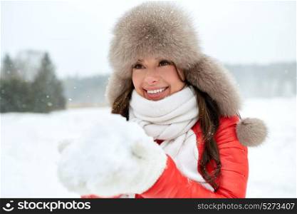 people, season and leisure concept - happy woman in winter fur hat with snow outdoors. happy woman in winter fur hat with snow outdoors