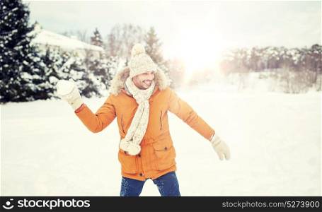 people, season and leisure concept - happy young man playing snowballs in winter. happy young man playing snowballs in winter