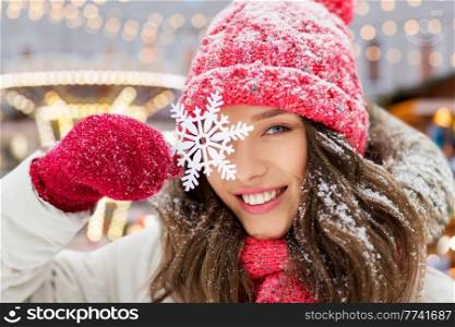 people, season and winter holidays concept - portrait of happy smiling teenage girl or young woman with snowflake over christmas lights in amusement park on background. portrait of teenage girl with snowflake in winter