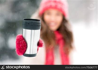 people, season, drinks and christmas concept - close up of young woman hand holding hot drink in tumbler or thermo cup outdoors in winter. hand holding tumbler or thermo cup in winter