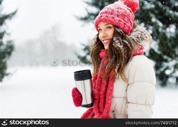 people, season, drinks and christmas concept - happy teenage girl or young woman with hot drink in tumbler outdoors in winter park. young woman with hot drink in tumbler in winter