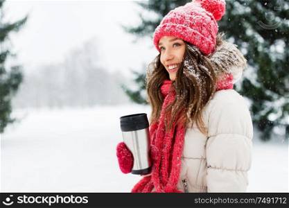 people, season, drinks and christmas concept - happy teenage girl or young woman with hot drink in tumbler outdoors in winter park. young woman with hot drink in tumbler in winter