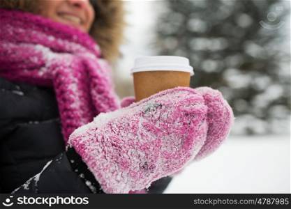 people, season, drinks and leisure concept - close up of woman hand with coffee cup outdoors in winter