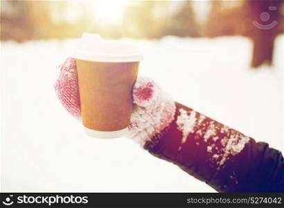 people, season, drinks and leisure concept - close up of woman hand with coffee cup outdoors in winter. close up of hand with coffee outdoors in winter