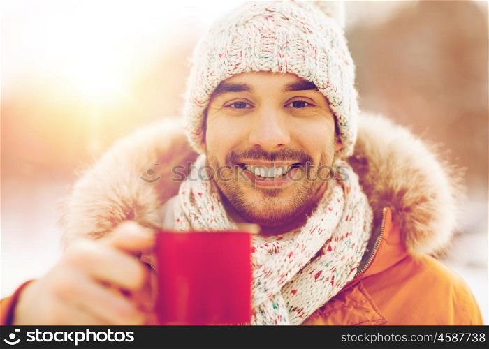 people, season, drinks and leisure concept - happy man with tea cup outdoors in winter