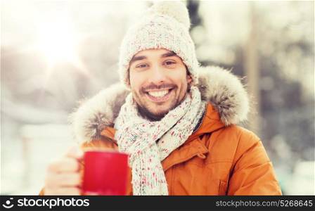 people, season, drinks and leisure concept - happy man with tea cup outdoors in winter. happy man with tea cup outdoors in winter