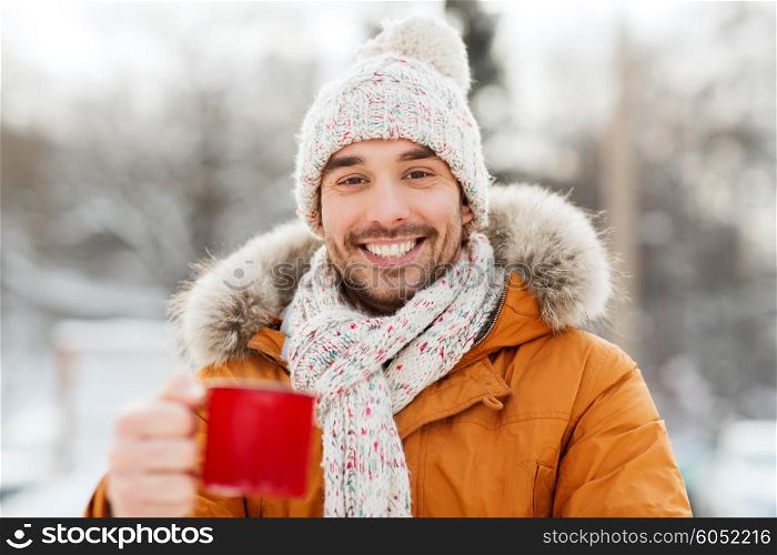 people, season, drinks and leisure concept - happy man with tea cup outdoors in winter