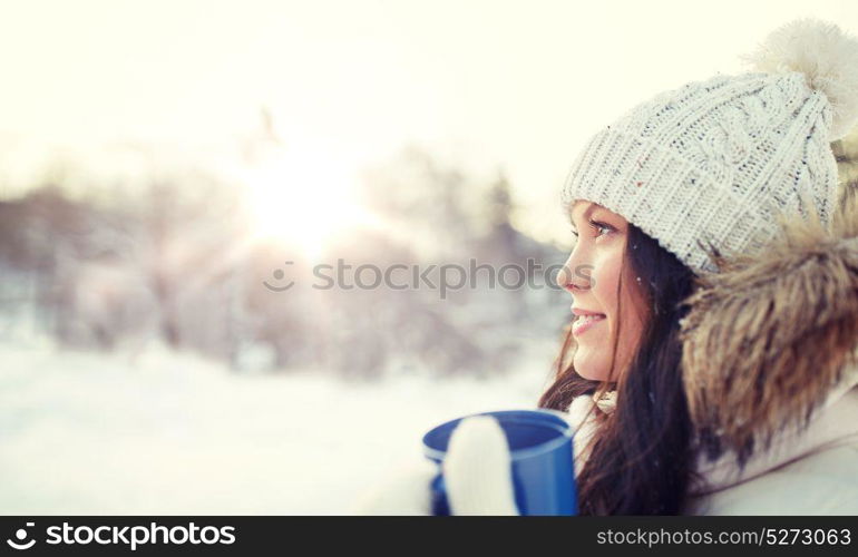 people, season, drinks and leisure concept - happy young woman with tea cup outdoors in winter. happy young woman with tea cup outdoors in winter