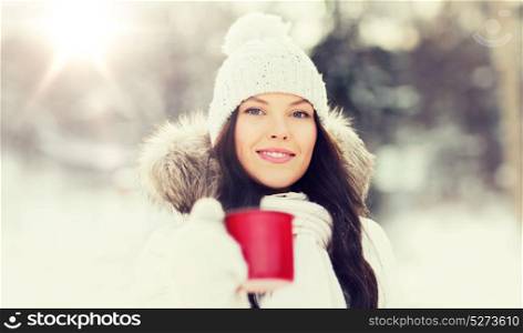 people, season, drinks and leisure concept - happy young woman with tea cup outdoors in winter. happy young woman with tea cup outdoors in winter