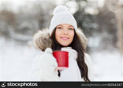 people, season, drinks and leisure concept - happy young woman with tea cup outdoors in winter
