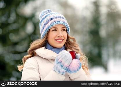 people, season, drinks and leisure concept - happy young woman with tea cup outdoors in winter. happy young woman with tea cup outdoors in winter