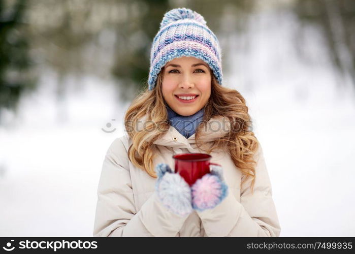 people, season, drinks and leisure concept - happy young woman with tea cup outdoors in winter. happy young woman with tea cup outdoors in winter