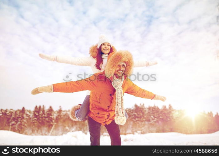 people, season, love and leisure concept - happy couple having fun over winter background