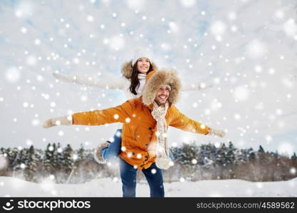 people, season, love and leisure concept - happy couple having fun over winter background