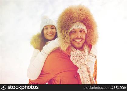 people, season, love and leisure concept - happy couple having fun over winter background