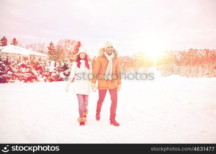 people, season, love and leisure concept - happy couple holding hands and walking along snowy winter field