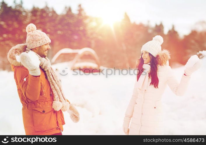 people, season, love and leisure concept - happy couple playing snowballs in winter