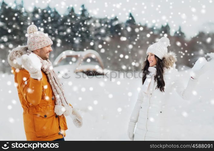 people, season, love and leisure concept - happy couple playing snowballs in winter