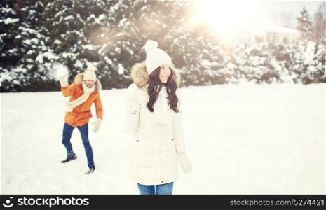 people, season, love and leisure concept - happy couple playing snowballs in winter. happy couple playing snowballs in winter