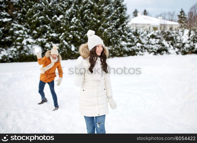 people, season, love and leisure concept - happy couple playing snowballs in winter