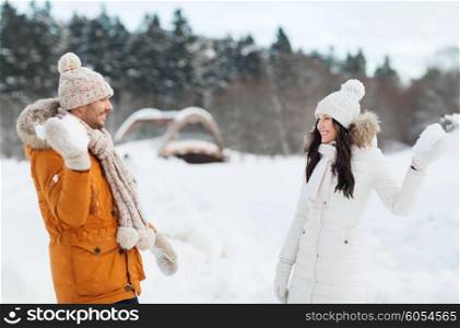 people, season, love and leisure concept - happy couple playing snowballs in winter
