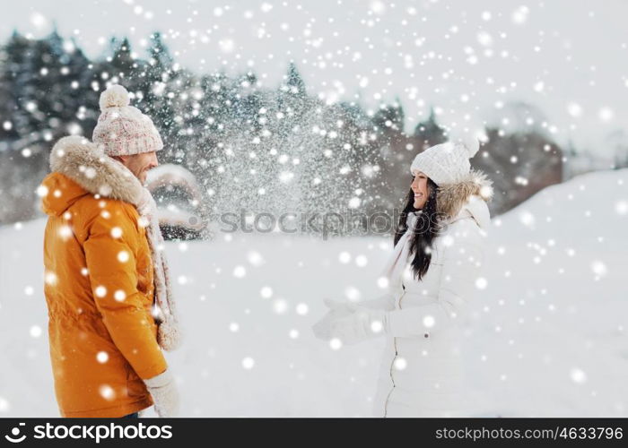 people, season, love and leisure concept - happy couple playing with snow in winter