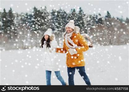 people, season, love and leisure concept - happy couple running over winter background