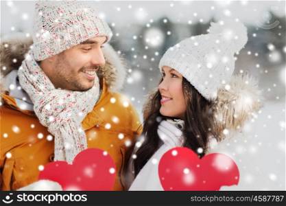 people, season, love and valentines day concept - happy couple holding blank red hearts over winter landscape