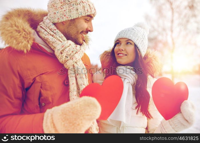 people, season, love and valentines day concept - happy couple holding blank red hearts over winter landscape