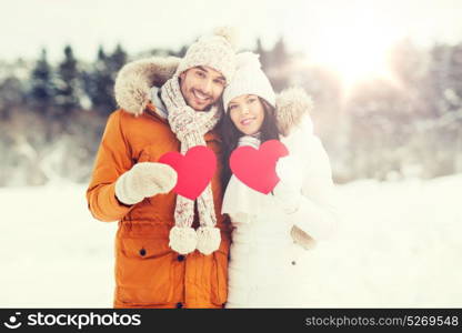 people, season, love and valentines day concept - happy couple holding blank red hearts over winter landscape. happy couple with red hearts over winter landscape