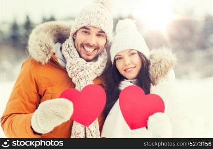 people, season, love and valentines day concept - happy couple holding blank red hearts over winter landscape. happy couple with red hearts over winter landscape