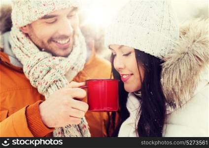 people, season, love, drinks and leisure concept - happy couple holding hot tea cups over winter landscape. happy couple with tea cups over winter landscape