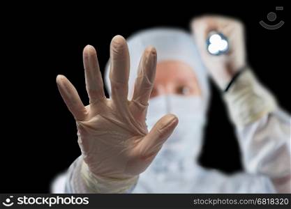 People shines a flashlight in protective clothing at the camera against a black background
