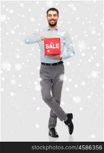 people, shopping, christmas, winter and holidays concept - smiling man holding red sale sign over snow background