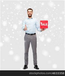 people, shopping, christmas, winter and holidays concept - smiling man holding red sale sign and showing thumbs up gesture