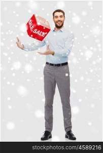 people, shopping, christmas, winter and holidays concept - smiling man playing with red sale sign over snow background