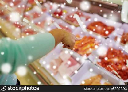 people, shopping, sale and food concept - customer hand pointing at meat on grocery stall over snow. customer hand pointing at meat on grocery stall