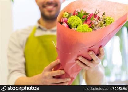 people, shopping, sale, floristry and consumerism concept - close up of happy florist man holding bunch wrapped in paper at flower shop
