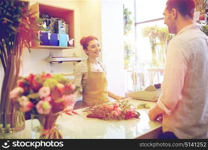 people, shopping, sale, floristry and consumerism concept - happy smiling florist woman and man or customer talking at flower shop. smiling florist woman and man at flower shop