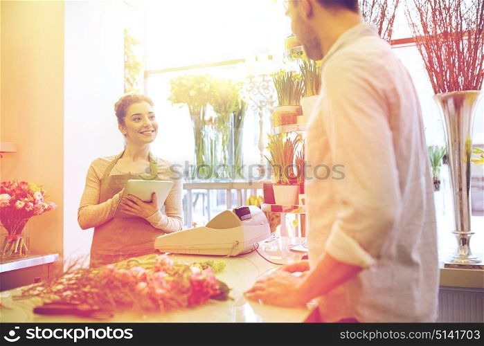 people, shopping, sale, floristry and consumerism concept - happy smiling florist woman with tablet pc computer and man or customer at flower shop. florist woman and man making order at flower shop