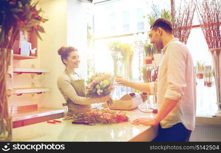 people, shopping, sale, floristry and consumerism concept - happy smiling florist woman making bouquet for and man or customer at flower shop. smiling florist woman and man at flower shop