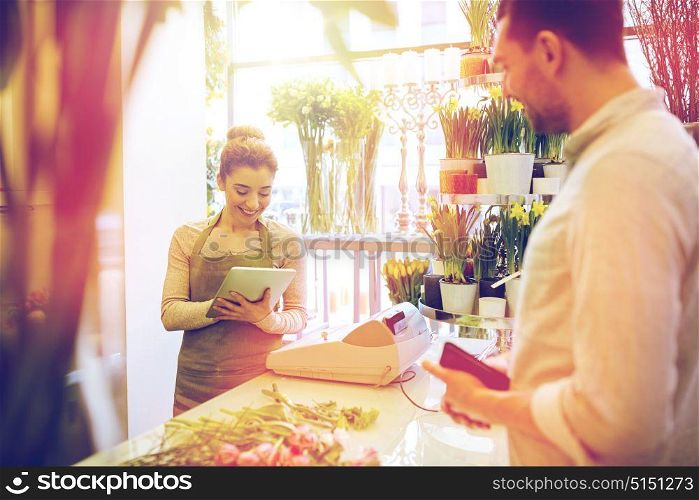 people, shopping, sale, floristry and consumerism concept - happy smiling florist woman with tablet pc computer and man with wallet at flower shop. florist woman and man making order at flower shop