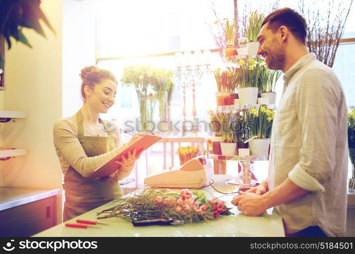 people, shopping, sale, floristry and consumerism concept - happy smiling florist woman with clipboard and man or customer making order at flower shop. florist woman and man making order at flower shop