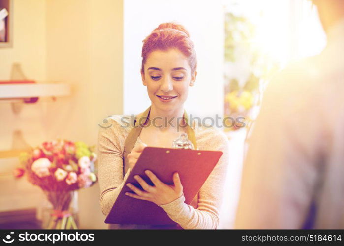 people, shopping, sale, floristry and consumerism concept - happy smiling florist woman with clipboard and man or customer making order at flower shop. florist woman and man making order at flower shop