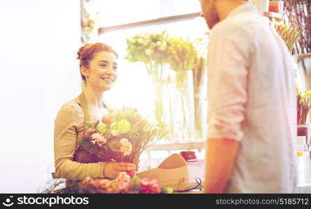 people, shopping, sale, floristry and consumerism concept - happy smiling florist woman making bouquet for and man or customer at flower shop. smiling florist woman and man at flower shop