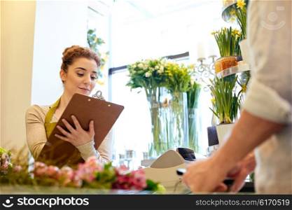 people, shopping, sale, floristry and consumerism concept - happy smiling florist woman with clipboard and man or customer making order at flower shop