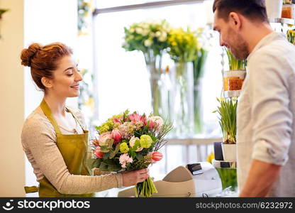 people, shopping, sale, floristry and consumerism concept - happy smiling florist woman making bouquet for and man or customer at flower shop