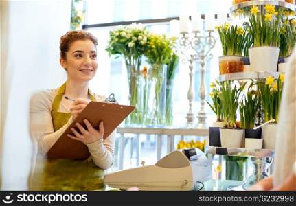 people, shopping, sale, floristry and consumerism concept - happy smiling florist woman with clipboard and man or customer making order at flower shop